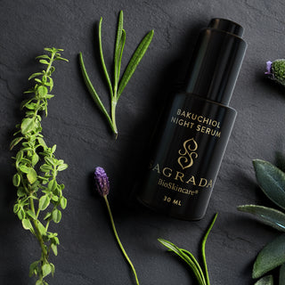Essential Serums Bakuchiol Night Serum bottle with fresh green and purple botanical leaves on black stone background.