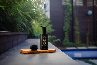 Black bottle lub for her and a black obsidian Yoni egg from Sagrada Bioskincare on a wooden board against a blurred natural background