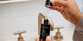 Bakuchiol Night Serum by Sagrada BioSkincare being dispensed with a dropper in a minimalist bathroom setting.