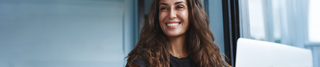 Smiling woman with long hair sitting by window – Sagrada BioSkincare Press Page Hero