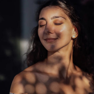 Girl's face with a satisfied look, closed eyes clean skin and covered by some outdoor shadows 