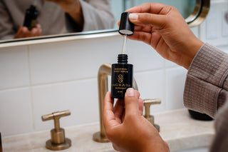 Applying Sagrada BioSkincare Bakuchiol Night Serum during a nighttime skincare ritual in a modern bathroom setting.