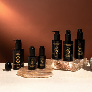 Sagrada skincare bundle featuring full-size products including cleansers, serums, mist, Lube for Her, and obsidian yoni egg on natural stone