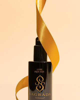Sagrada Lube for Her elegantly wrapped with a gold ribbon, celebrating intimate self-care as part of a festive holiday ritual