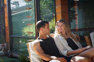 Smiling couple relaxing together in a sunlit outdoor space, representing connection, intimacy, and the benefits of using Sagrada Lube for Her